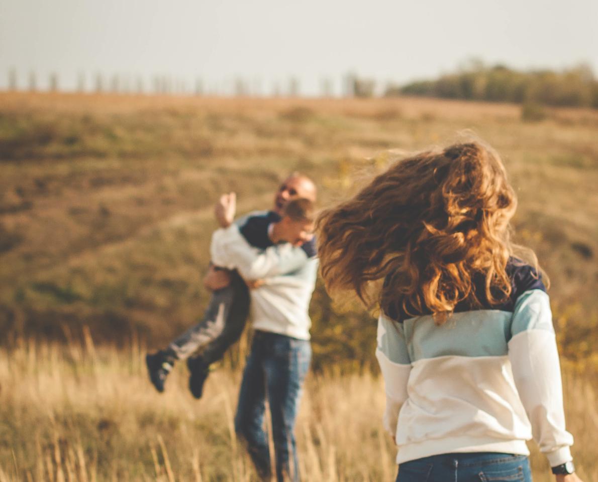 Ouders en zoon Mama en papa die samen met hun zoon aan het spelen zijn in een veld.